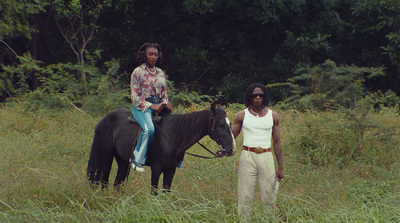 a man and a woman riding on the back of a black horse