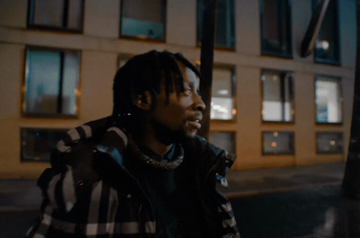 a man with dreadlocks standing in front of a building