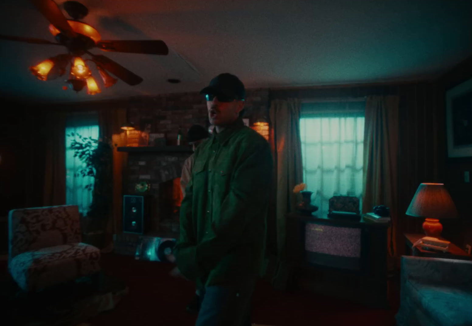 a man standing in a room with a ceiling fan