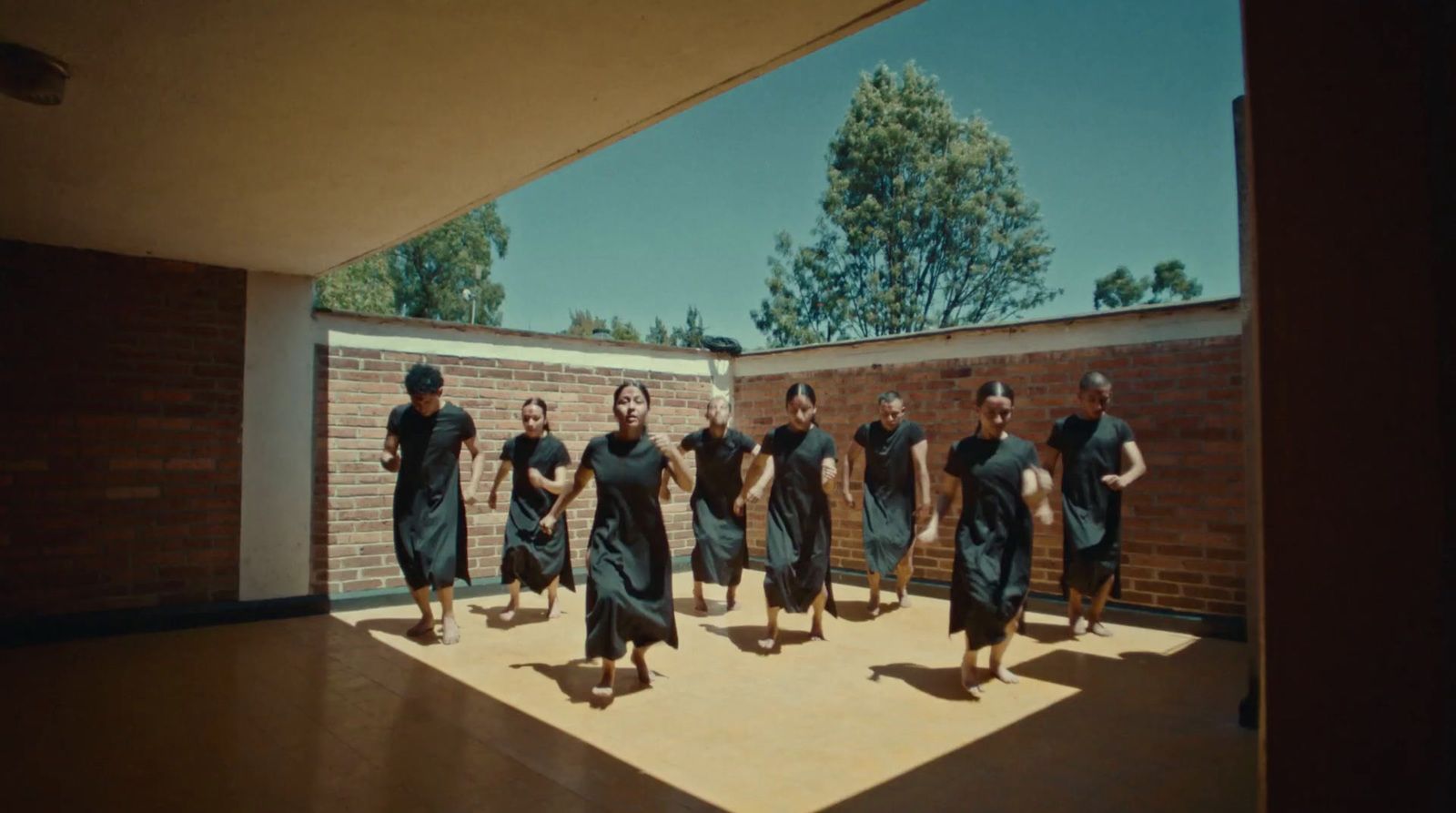 a group of women in black dresses walking across a floor