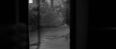 a black and white photo of a person looking out a window