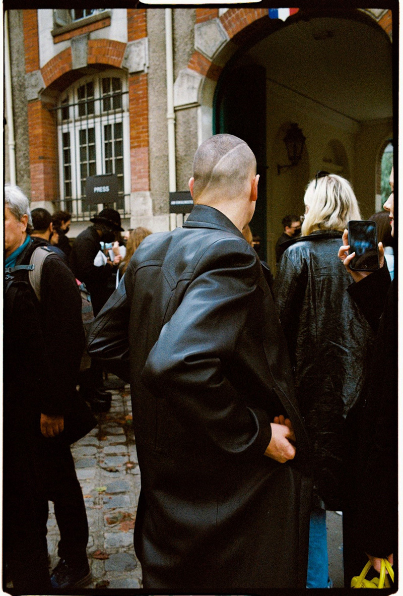 a man in a black coat standing in front of a building