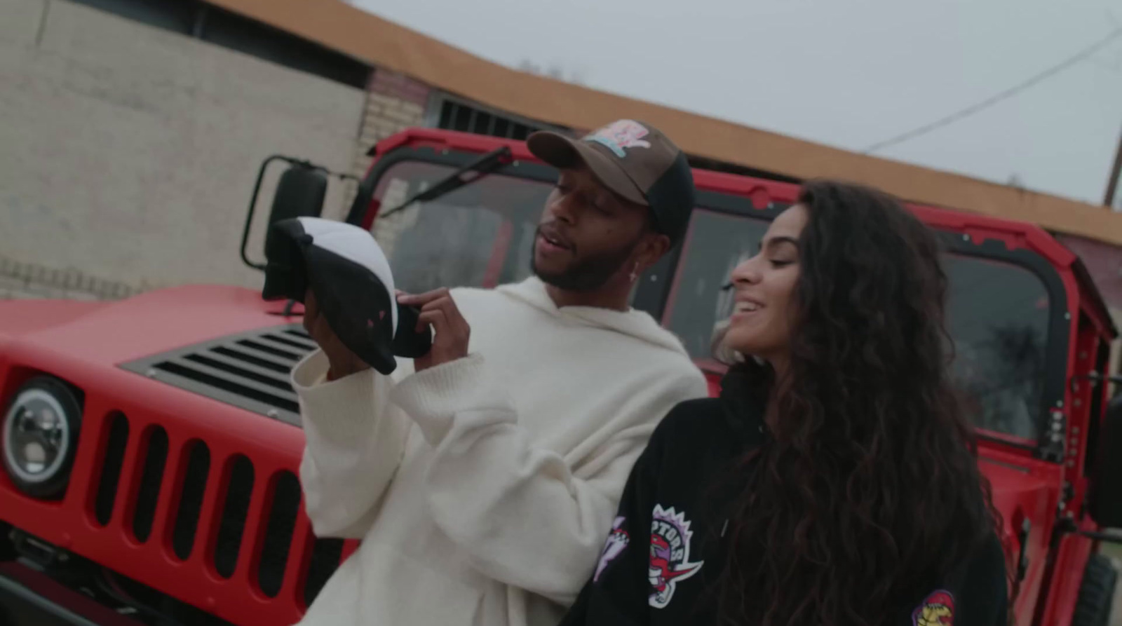 a man and a woman standing in front of a red truck