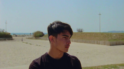 a young man standing in front of a sandy beach