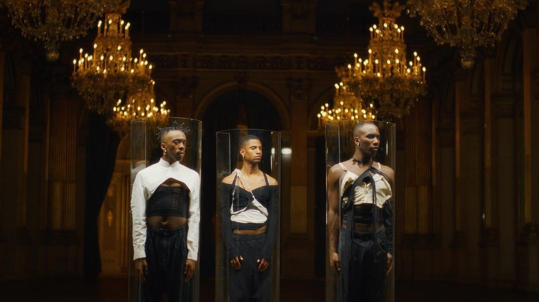 a group of three mannequins standing in front of a chandelier