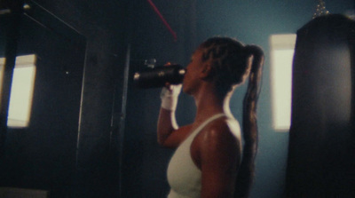 a woman standing in front of a mirror drinking from a bottle