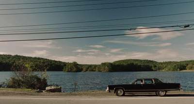 a black truck parked on the side of a road next to a lake