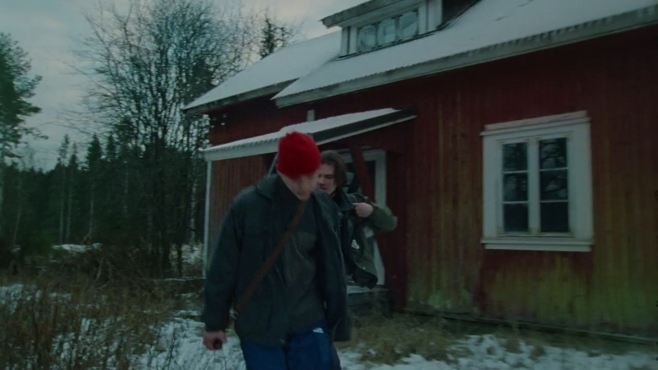 a man wearing a red hat standing in front of a red house