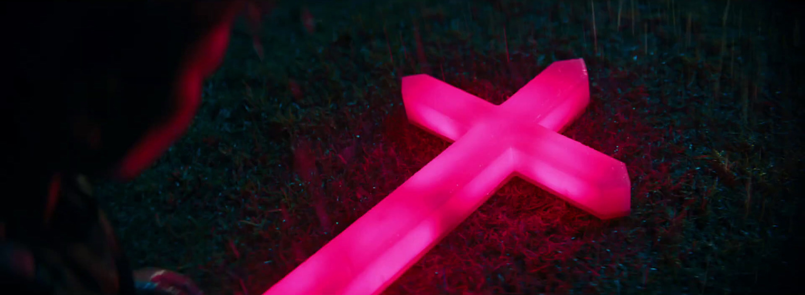 a pink cross laying on the ground in the dark