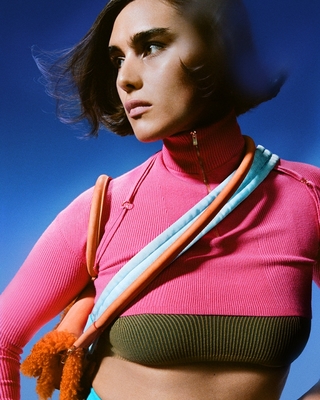 a woman wearing a pink top and a multicolored tie around her neck