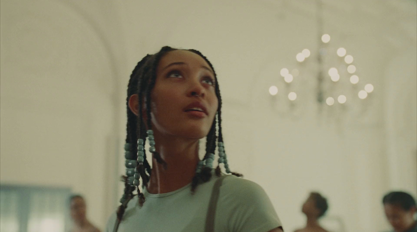 a woman with dreadlocks standing in front of a chandelier