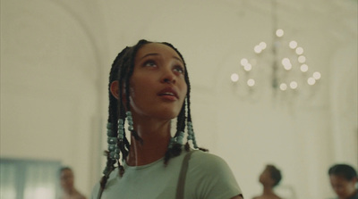 a woman with dreadlocks standing in front of a chandelier