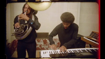 a man playing a keyboard next to another man