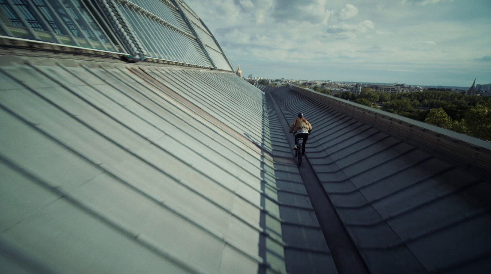 a person standing on a roof next to a tall building