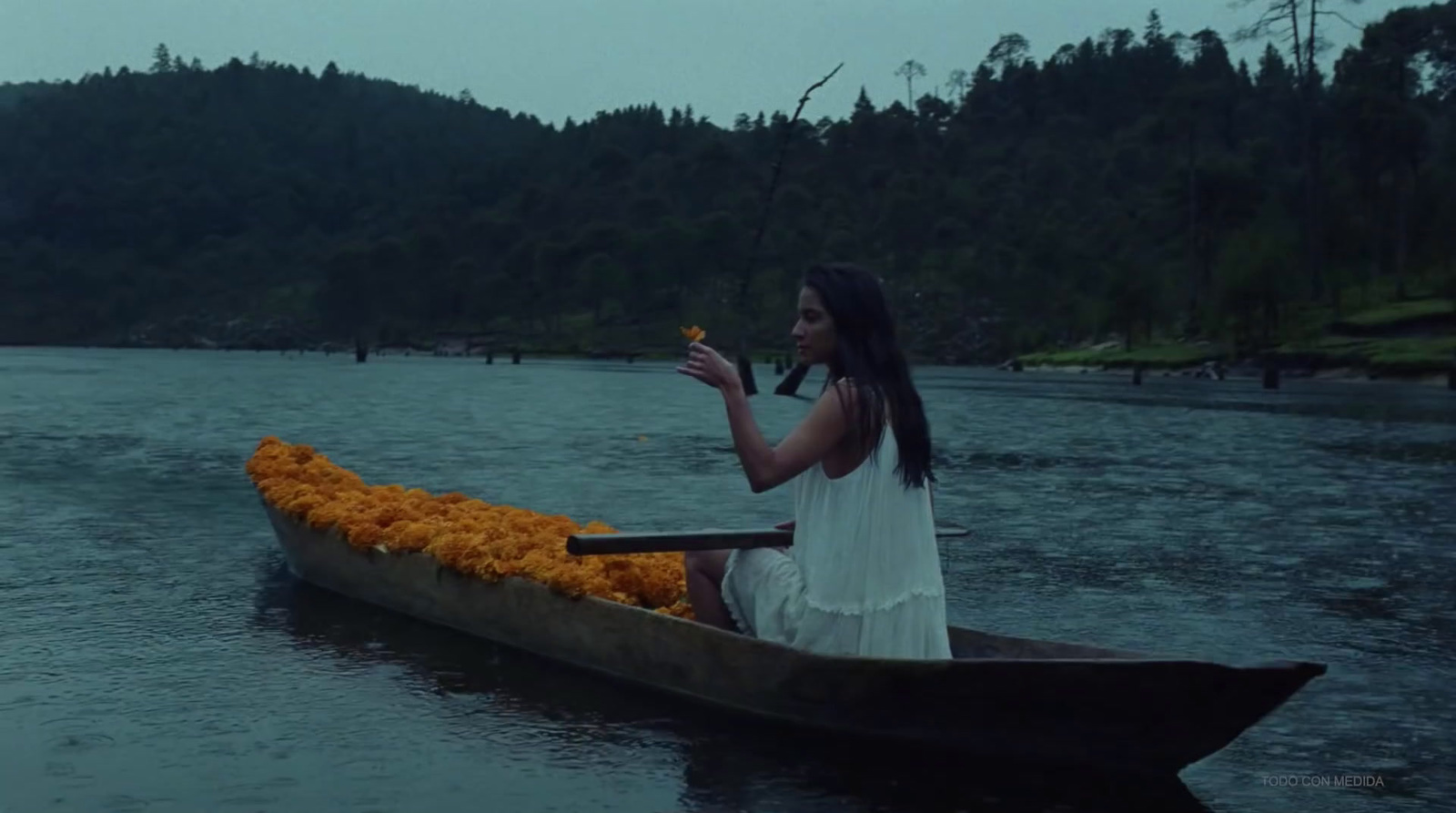 a woman sitting in a boat filled with orange flowers