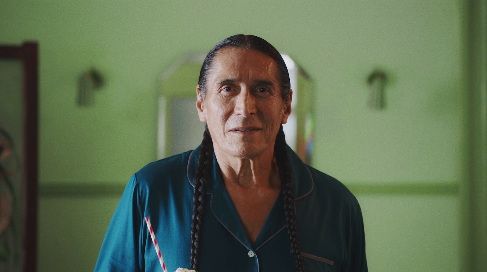 a man with long braids standing in a green room