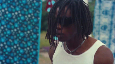 a man with dreadlocks standing next to a surfboard