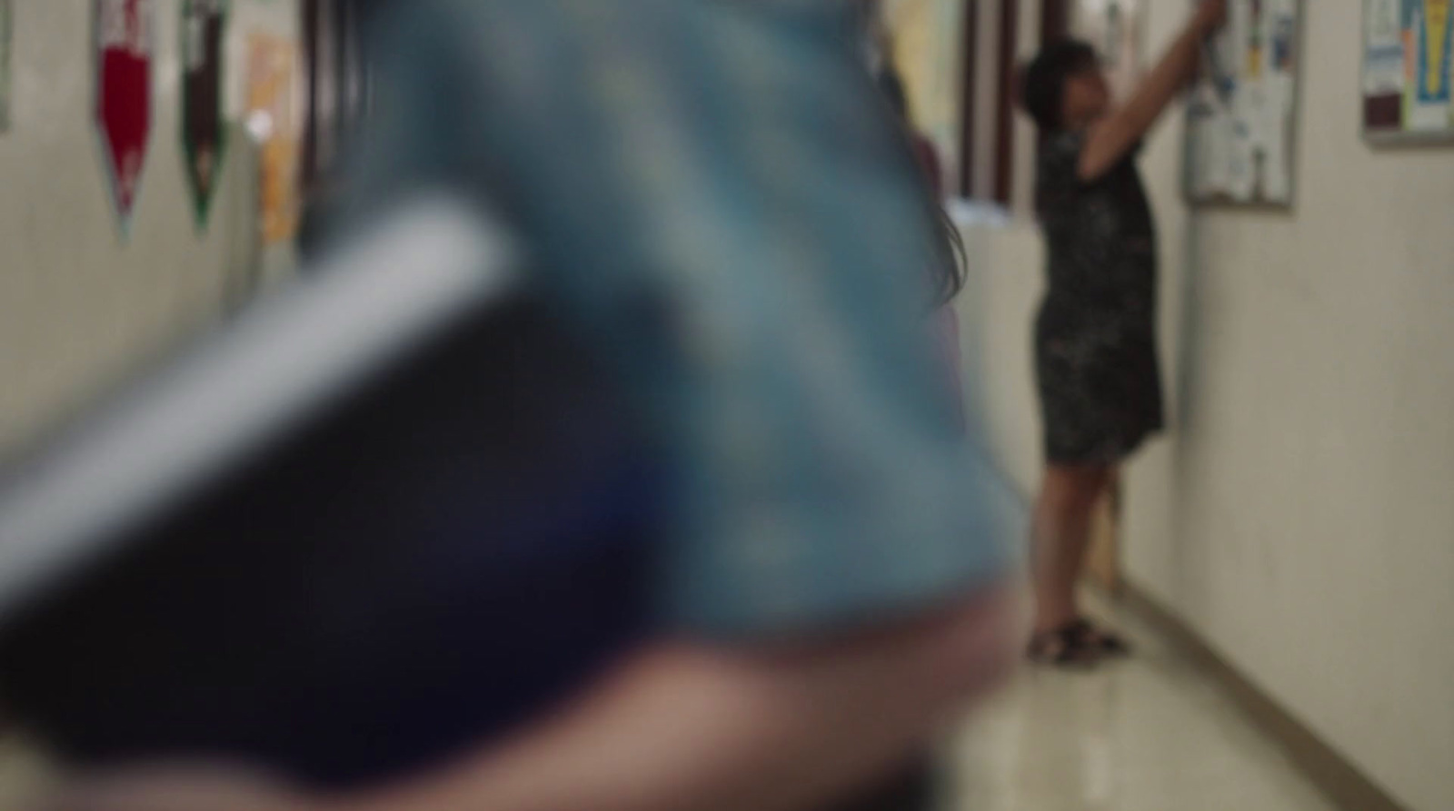 a woman standing in a hallway next to a wall with pictures on it