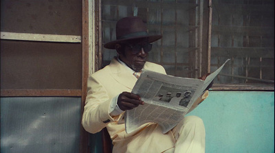 a man in a suit and hat reading a newspaper