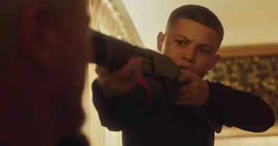 a young boy pointing a gun at the camera