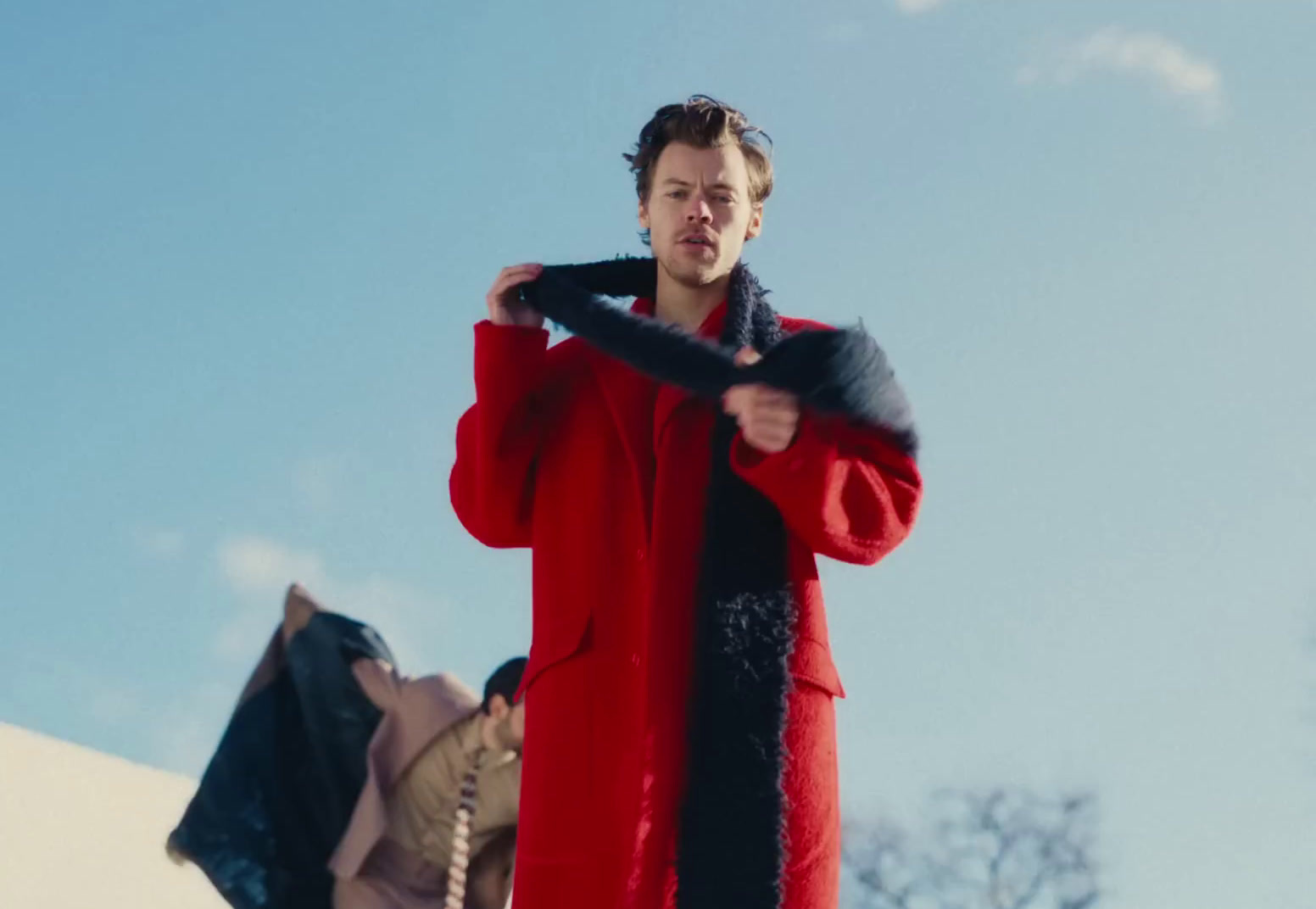 a man in a red coat holding a black scarf