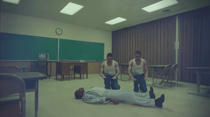 two men standing over a man laying on the floor