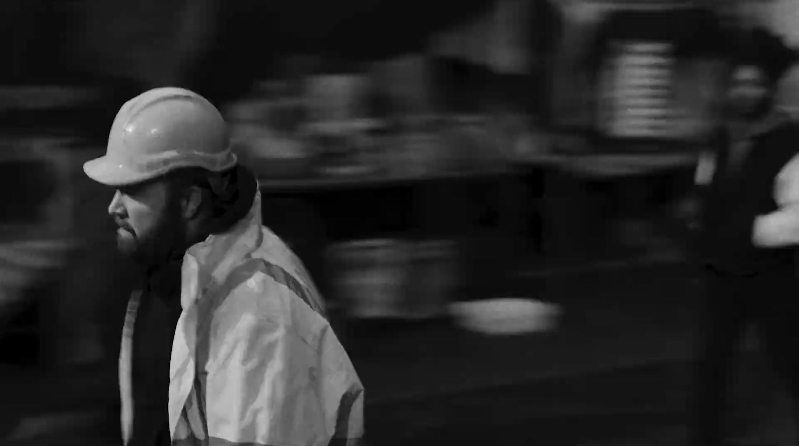 a black and white photo of a man wearing a hard hat