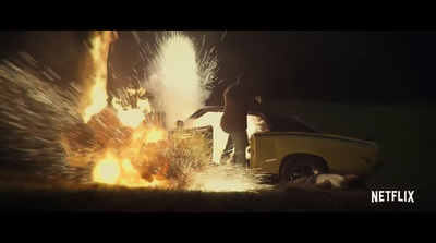 a car on fire with a man standing next to it