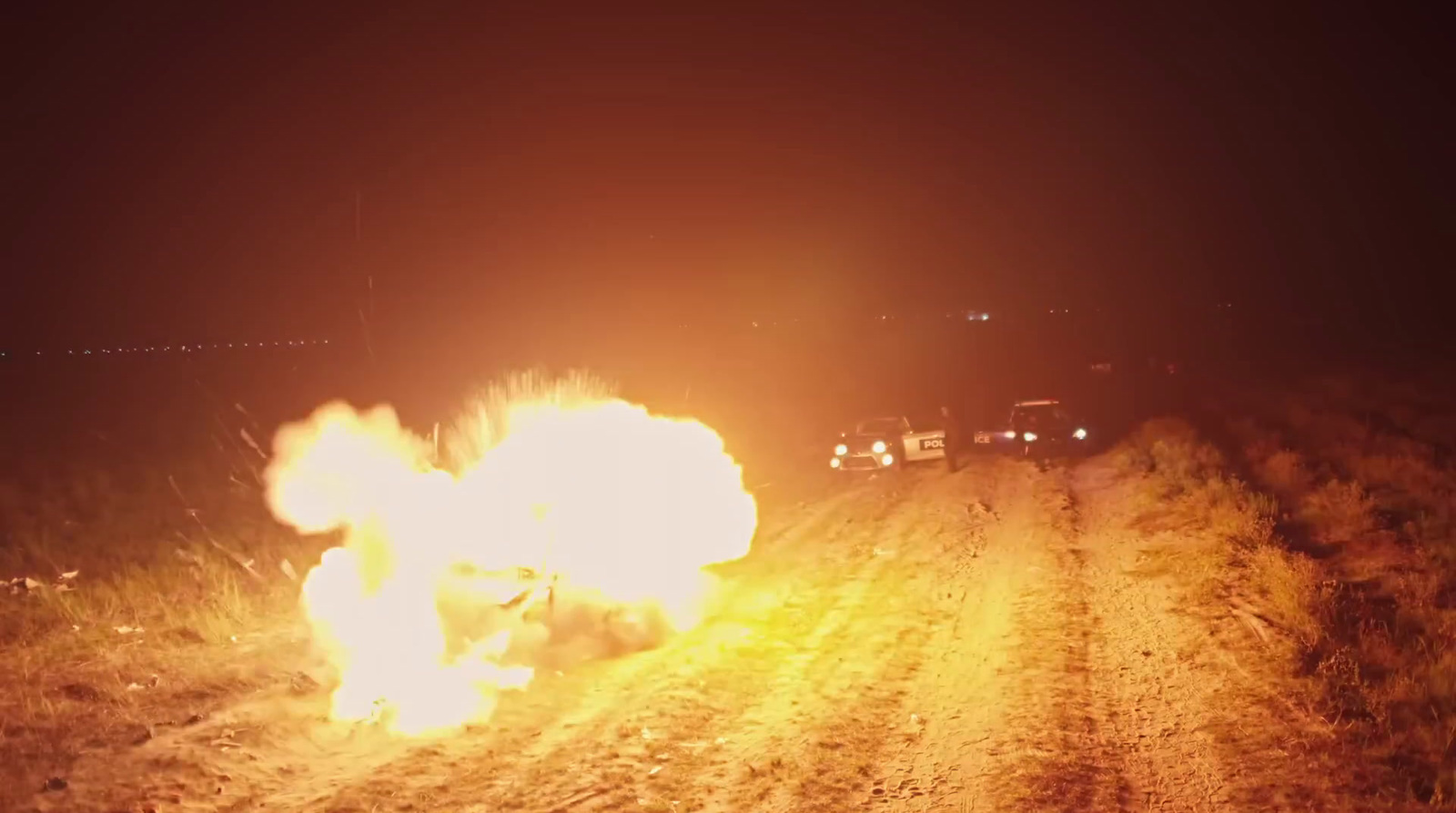 a car on fire on a dirt road at night