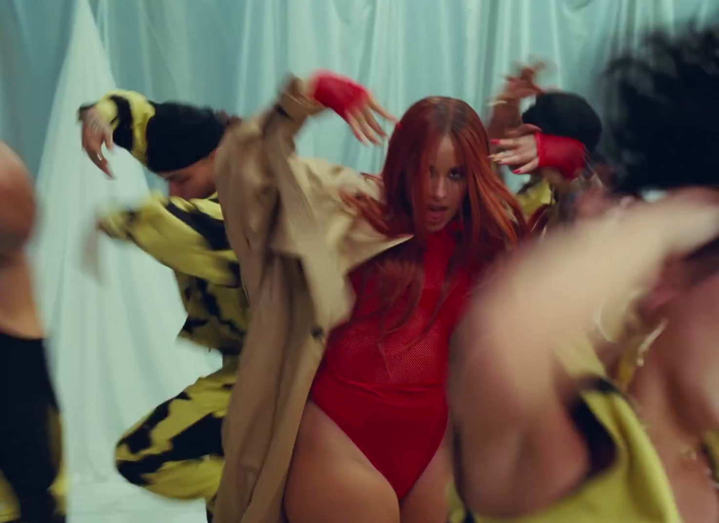 a woman in a red bodysuit dancing in front of a group of people