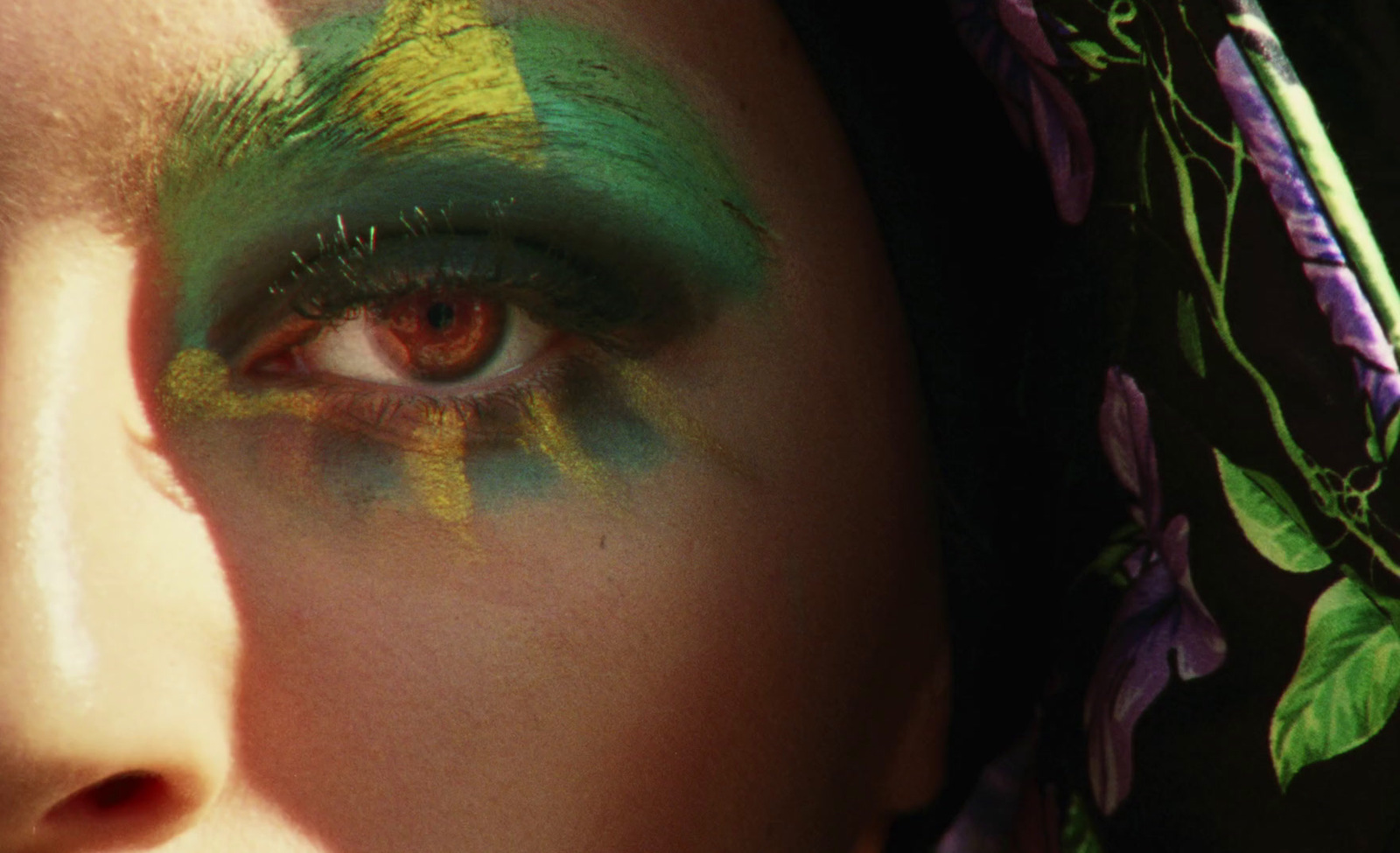 a close up of a woman's face with green and yellow makeup