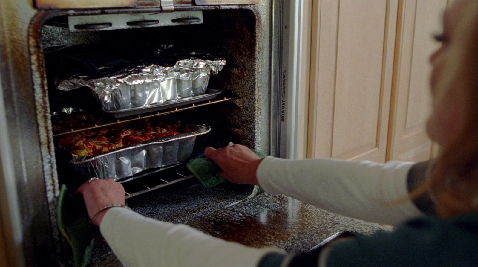 a woman taking food out of an oven