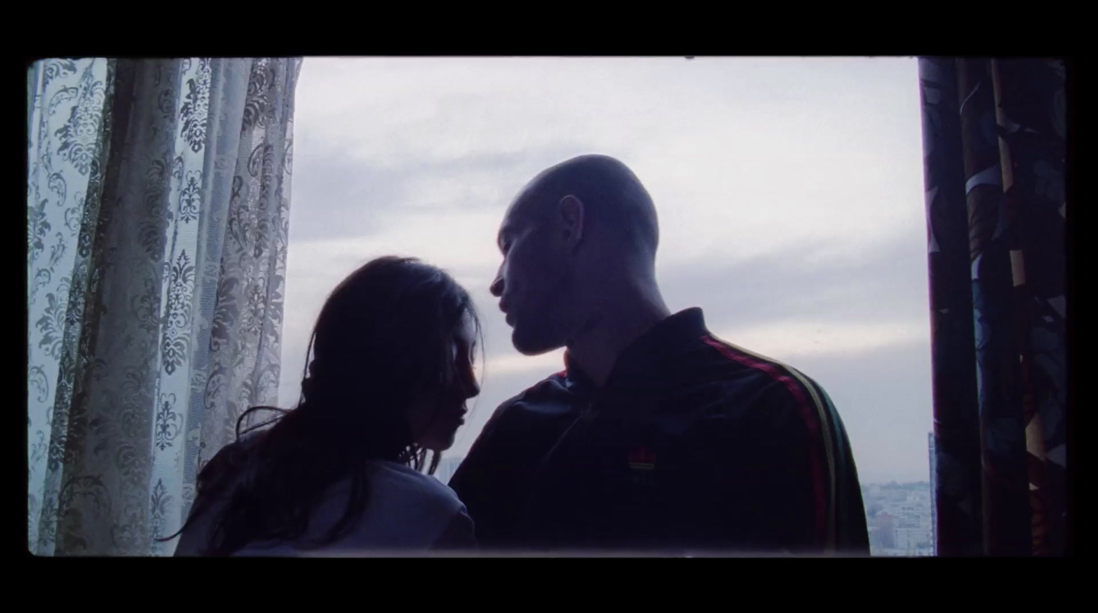 a man standing next to a woman near a window