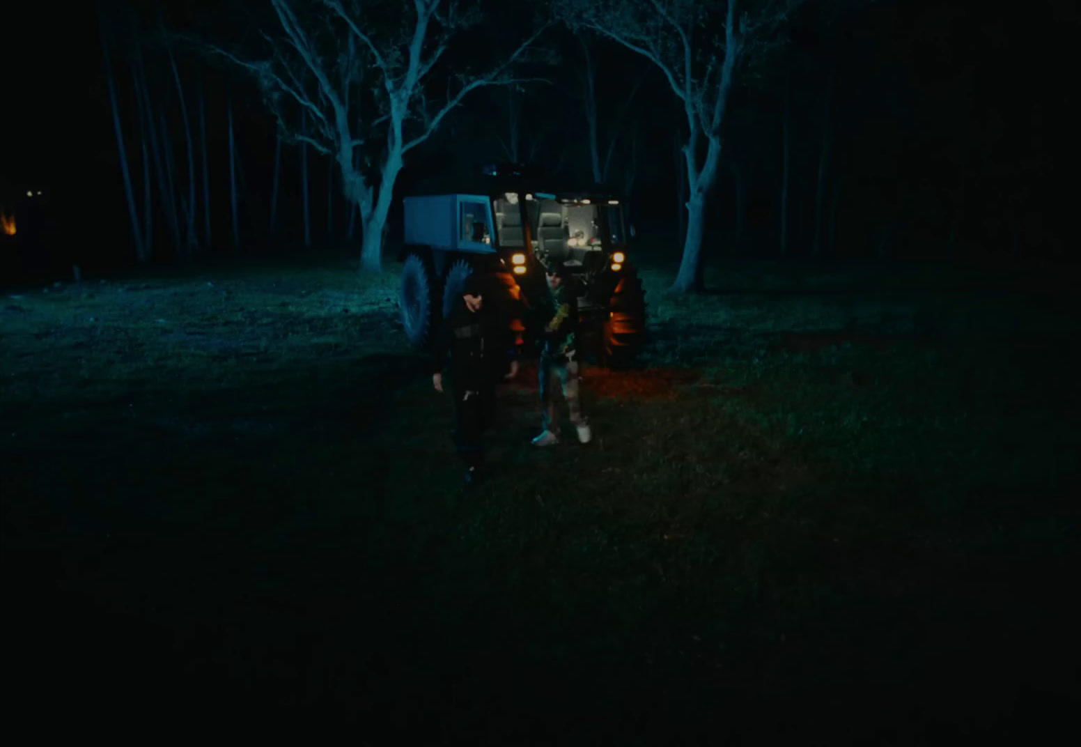 a couple of people standing next to a truck in the dark