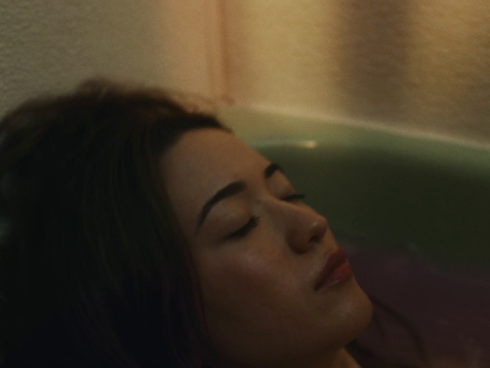 a woman laying in a bathtub with her eyes closed