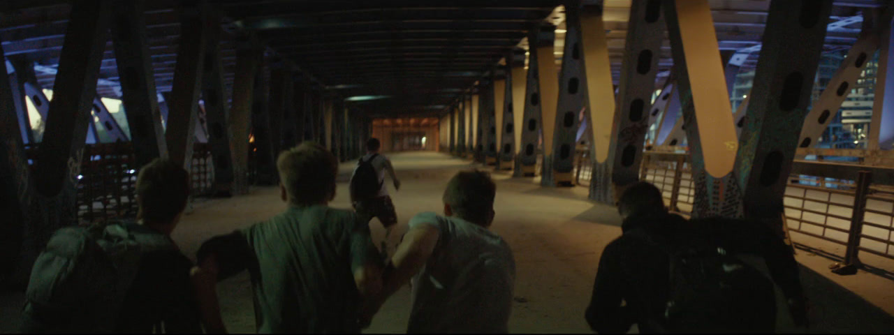 a group of people walking across a bridge at night