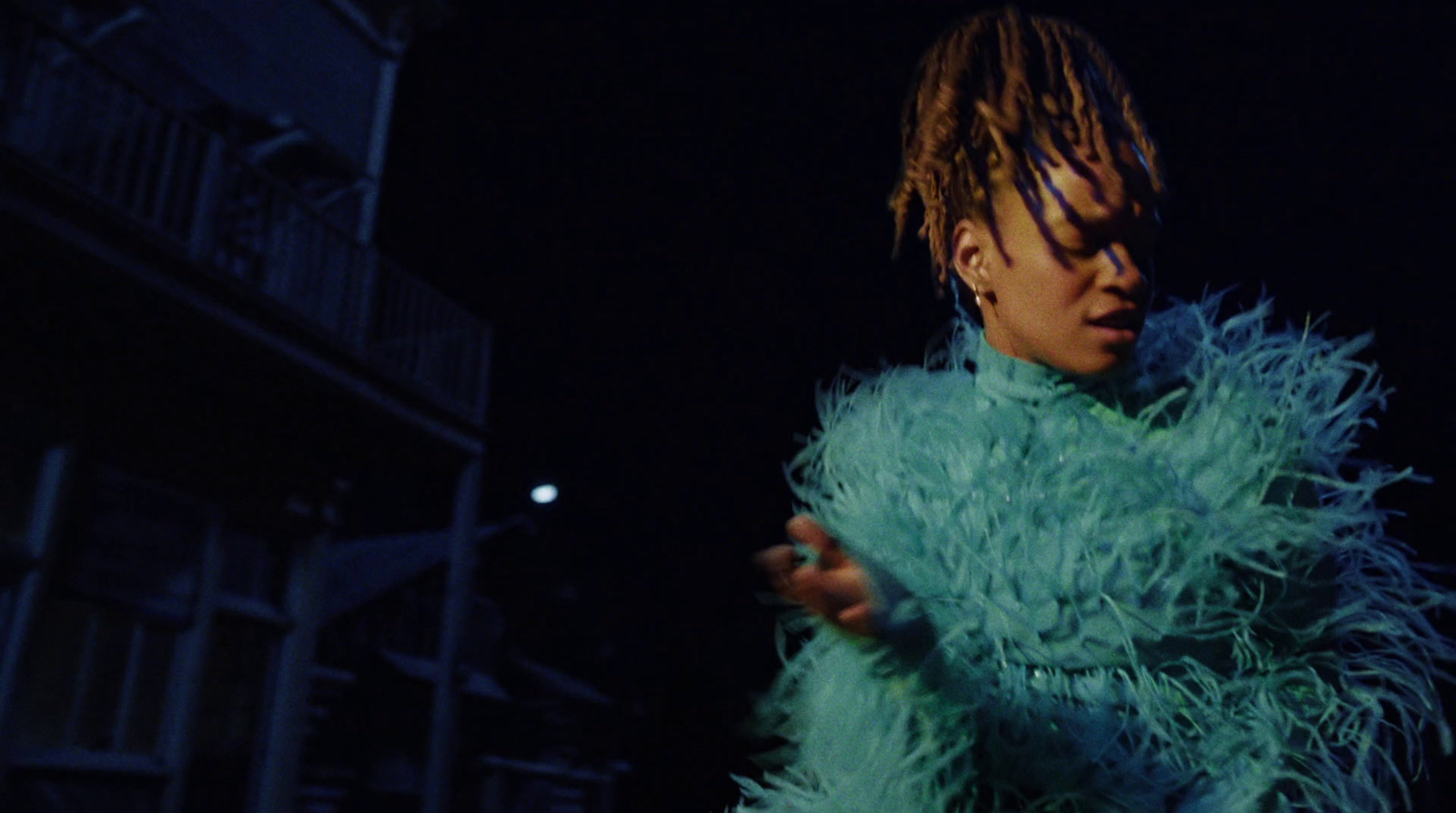 a person with dreadlocks standing in a dark room