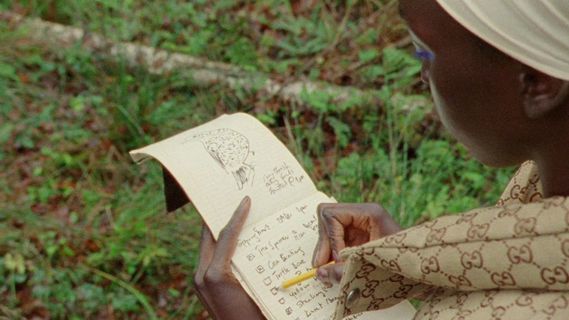 a woman is writing on a notebook outside