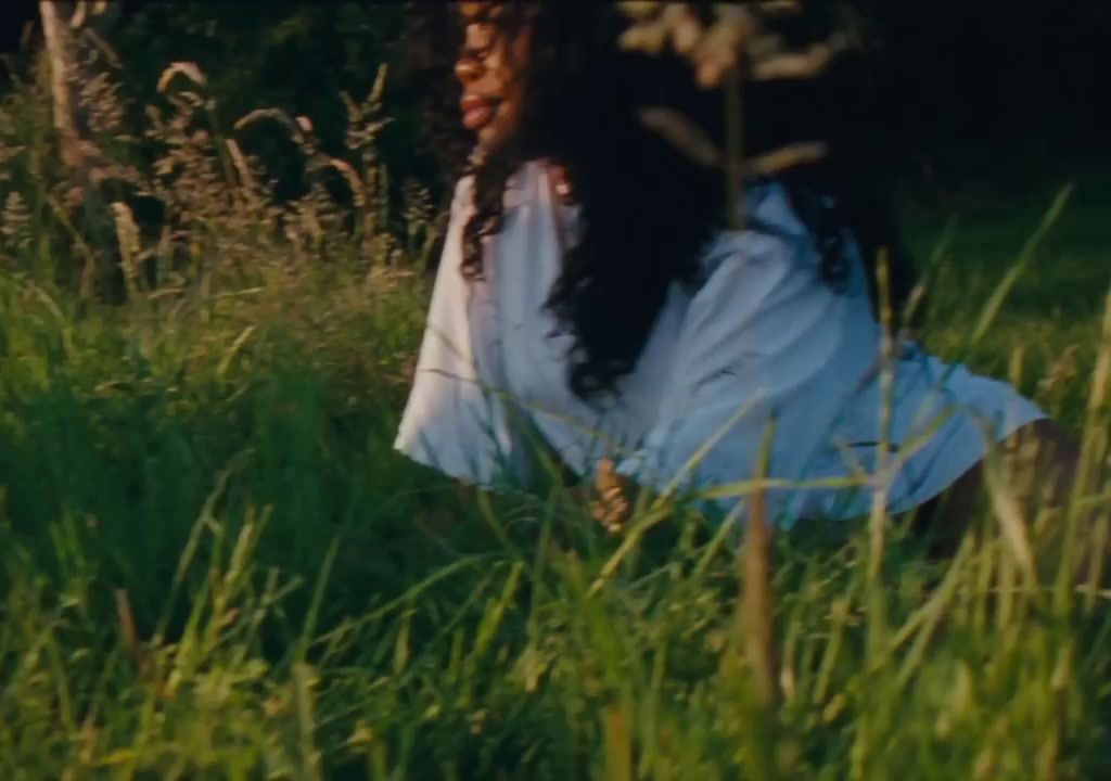 a woman sitting in a field of tall grass