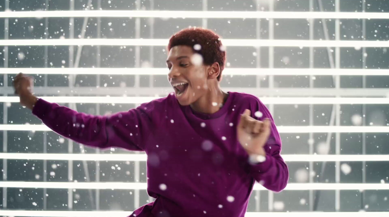 a man in a purple shirt is dancing in the snow