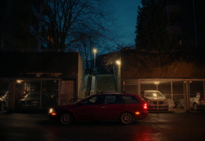 a red car parked in front of a building at night