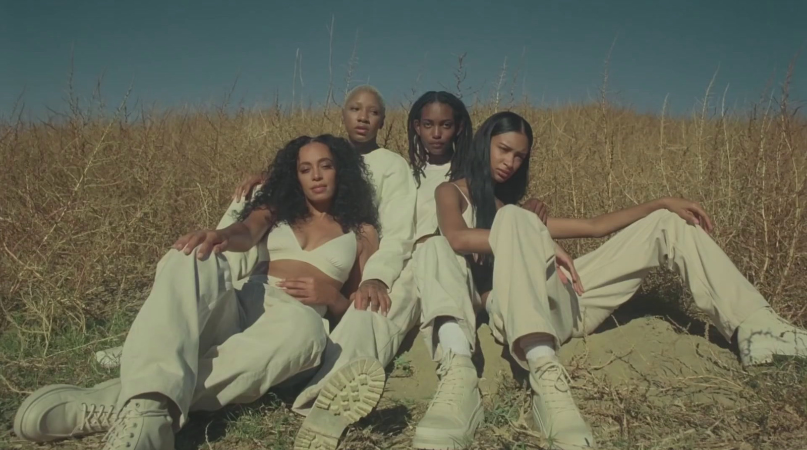 a group of people sitting on top of a grass covered field