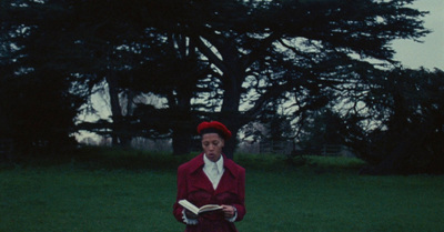 a woman standing in a field holding a book