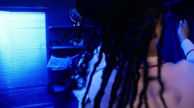 a woman with dreadlocks standing in front of a window