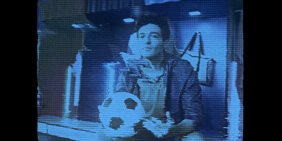 a man holding a soccer ball in front of a television screen