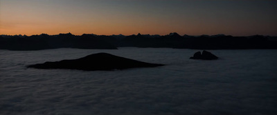 the sun is setting over the clouds and mountains