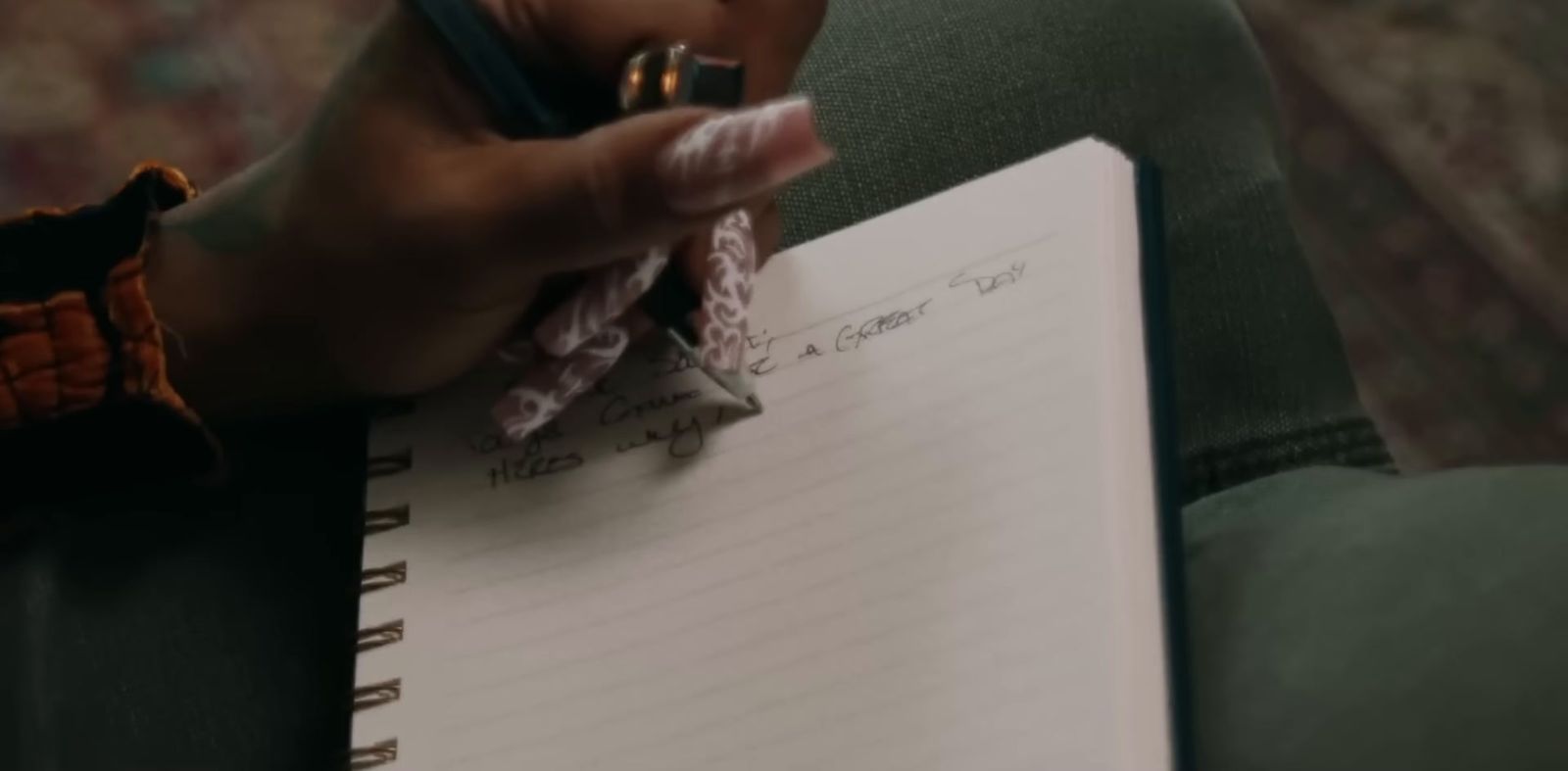 a person holding a pen and writing on a notebook