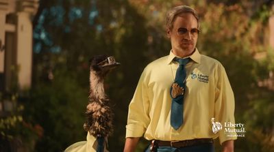 a man in a yellow shirt and tie standing next to an ostrich