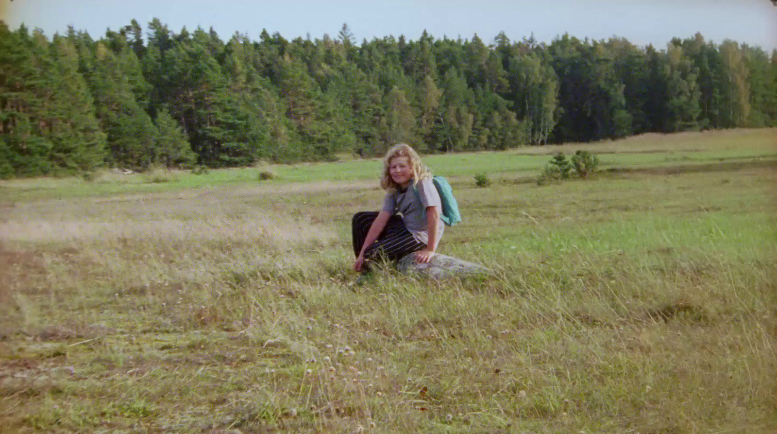 a man kneeling down in a field with a backpack