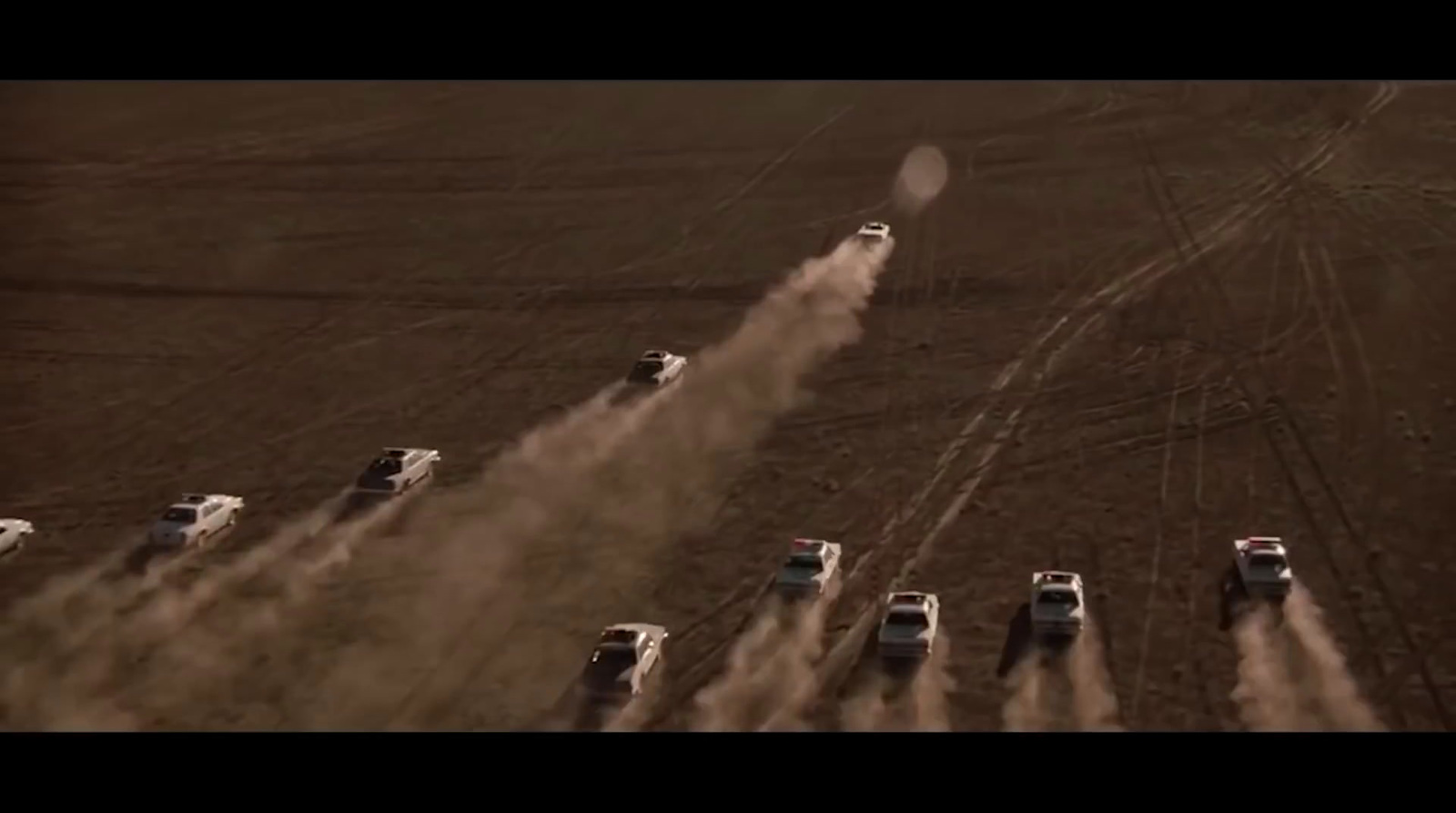 a group of trucks driving down a dirt road